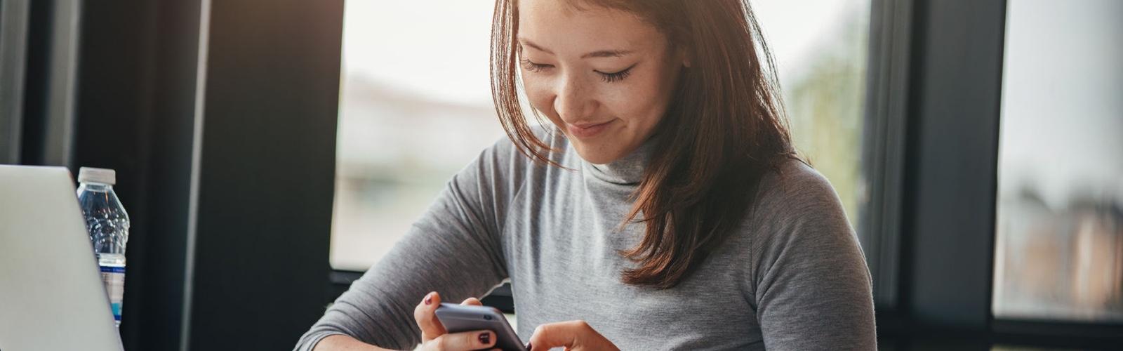 Close up of a woman smiling while looking at her phone