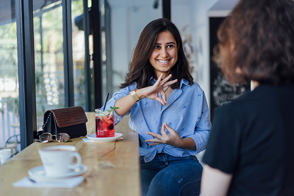 A woman using sign language to communicate in a coffee shop.