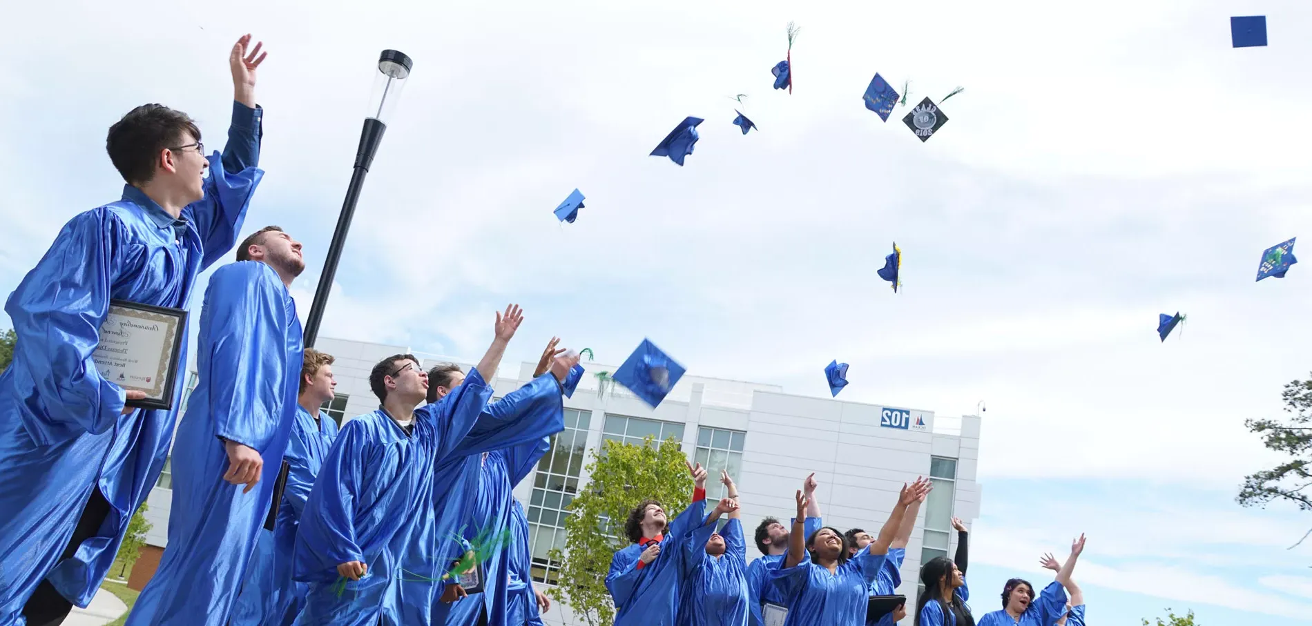 students from the Achievement center tossing their caps at graduation