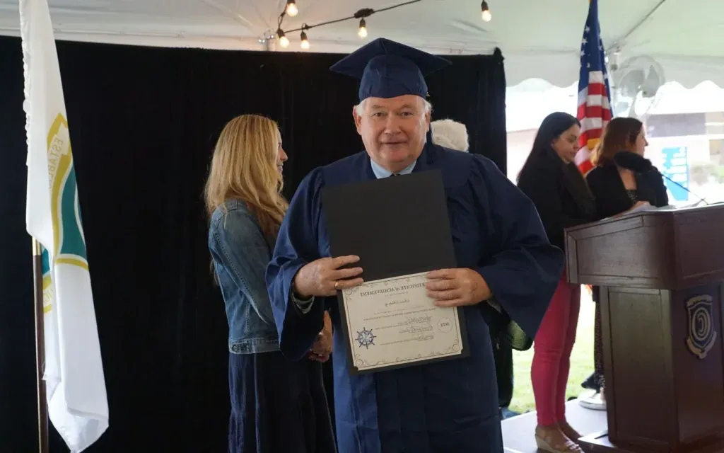 Male graduate posing with is diploma at graduation